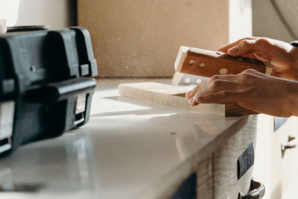 Hands smoothing a softwood board with a sanding block